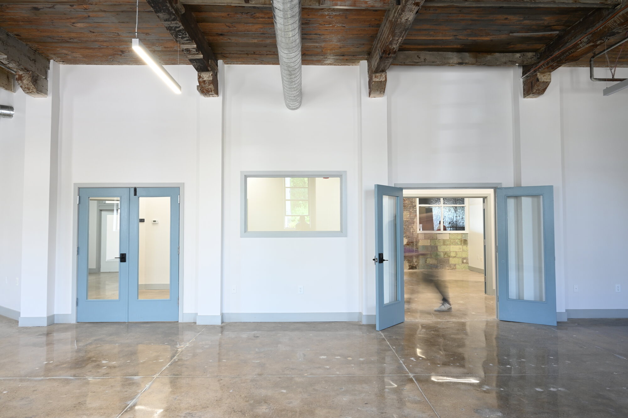 Bright finished studio with exposed timber ceiling and blue doors at 101 Washington Street
